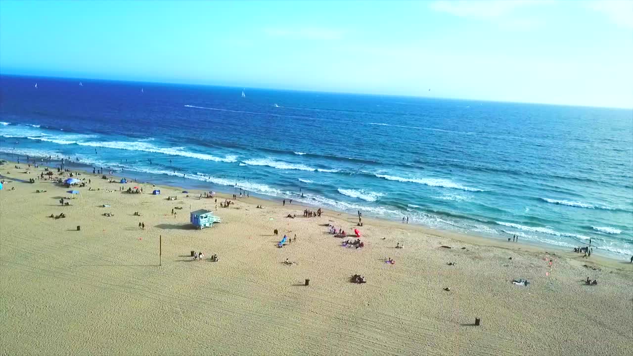 Sunny day in Venice beach California drone ocean view over sand panning left.
