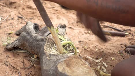 close-up of african man splicing wood with axe to make an arrow