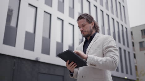 smart businessman writing on tablet device outdoors near the business center