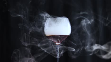 vaso lleno de cola líquido oscuro y humo con fondo negro