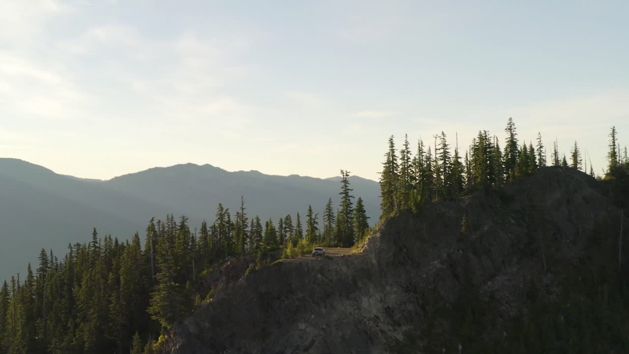 final de la ruta panorámica en la cima del pico de la montaña, el camión fuera de la carretera se encuentra solo en el borde del acantilado, antena ascendente, inclinación hacia abajo, movimiento cinematográfico en 4k