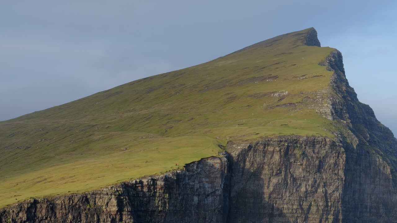 Majestic view of a sheer cliff with a green grassy top in the Faroe Islands
