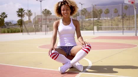 pretty young female athlete sits on basketball