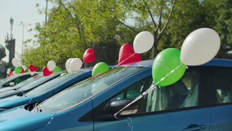 a row of cars decorated with helium-filled multi-colored ballons, for a party or a wedding