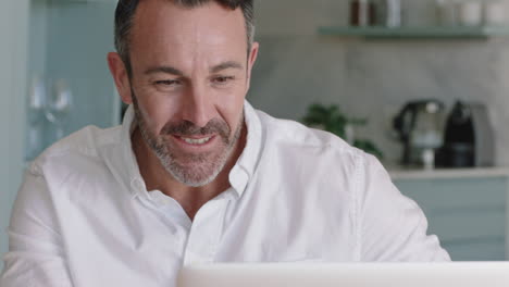 Hombre-Atractivo-Usando-Una-Computadora-Portátil-Trabajando-En-Casa-Navegando-En-Línea-Leyendo-Mensajes-De-Redes-Sociales-En-Una-Computadora-Tomando-Café-Disfrutando-De-La-Comunicación-Digital