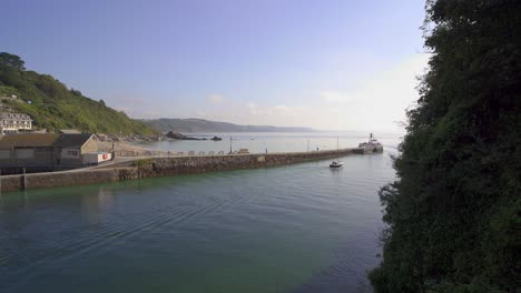 un barco de recreo sale del estuario del looe a lo largo del malecón