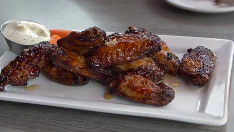 person eating glazed chicken wings at a restaurant