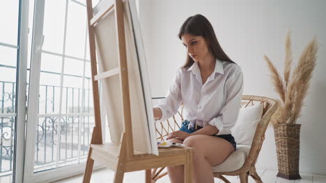 lady artist works drawing picture on wooden easel in studio