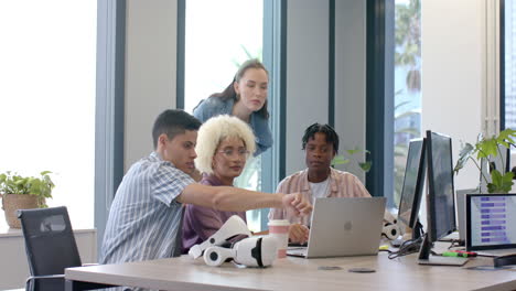 collaborating in office, diverse team using laptop and vr headsets for project
