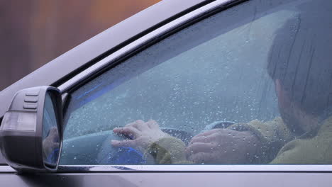 stressful adult male sitting in car interior on rainy day, human emotions, close-up shot