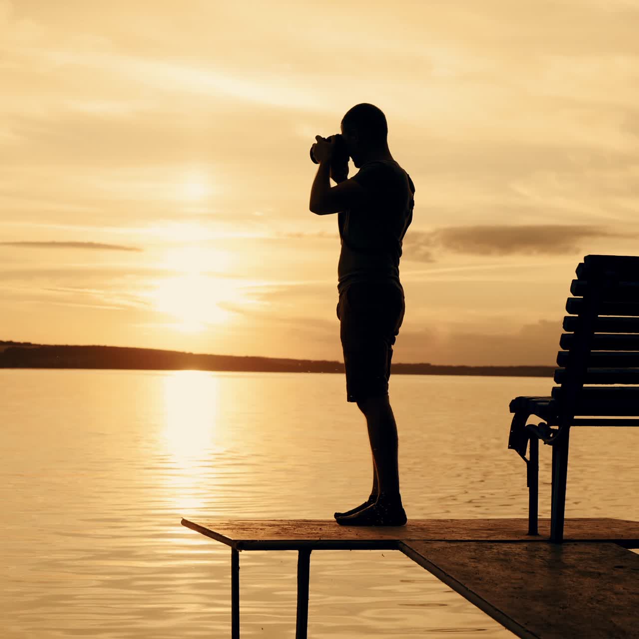 Photographer taking picture of landscape during sunset. Silhouette of people swimming in the river at sunset