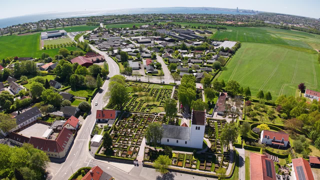 Aerial shot of a Danish countryside village with residential houses, farmland, and a church at the center