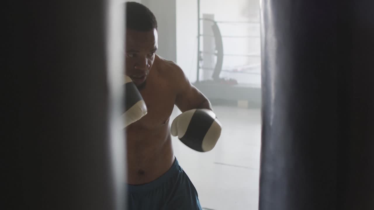 Vídeo de homem afro-americano em forma praticando boxe na academia.