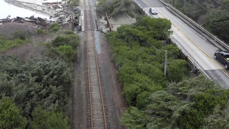 Rising-aerial-shot-over-railroad-tracks-and-road-with-cars