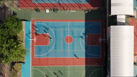 basketball court in the park with active people playing on a sunny day