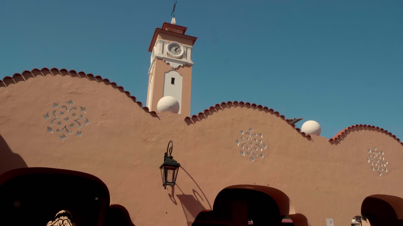 Tetti bianchi ondulati distintivi e una torre dell'orologio di un edificio simbolo sotto un cielo azzurro e limpido a Santa Cruz de Tenerife. Ripresa esterna dal basso.
