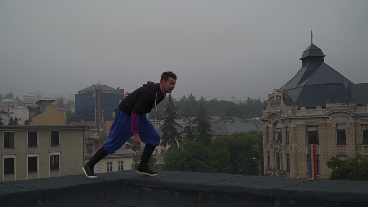 Practicing parkour by the roofs of Romania during the early evening - wide pan