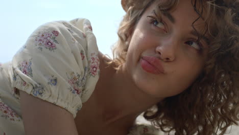 portrait curly woman playfully adjusting straw hat on head relaxing on seashore.