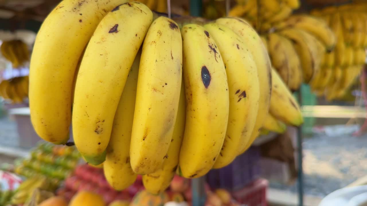 Fruit shop, A static closeup shot showing a bunch of ripe banana and other fruits in depth of field for sale at the fruit stall in India