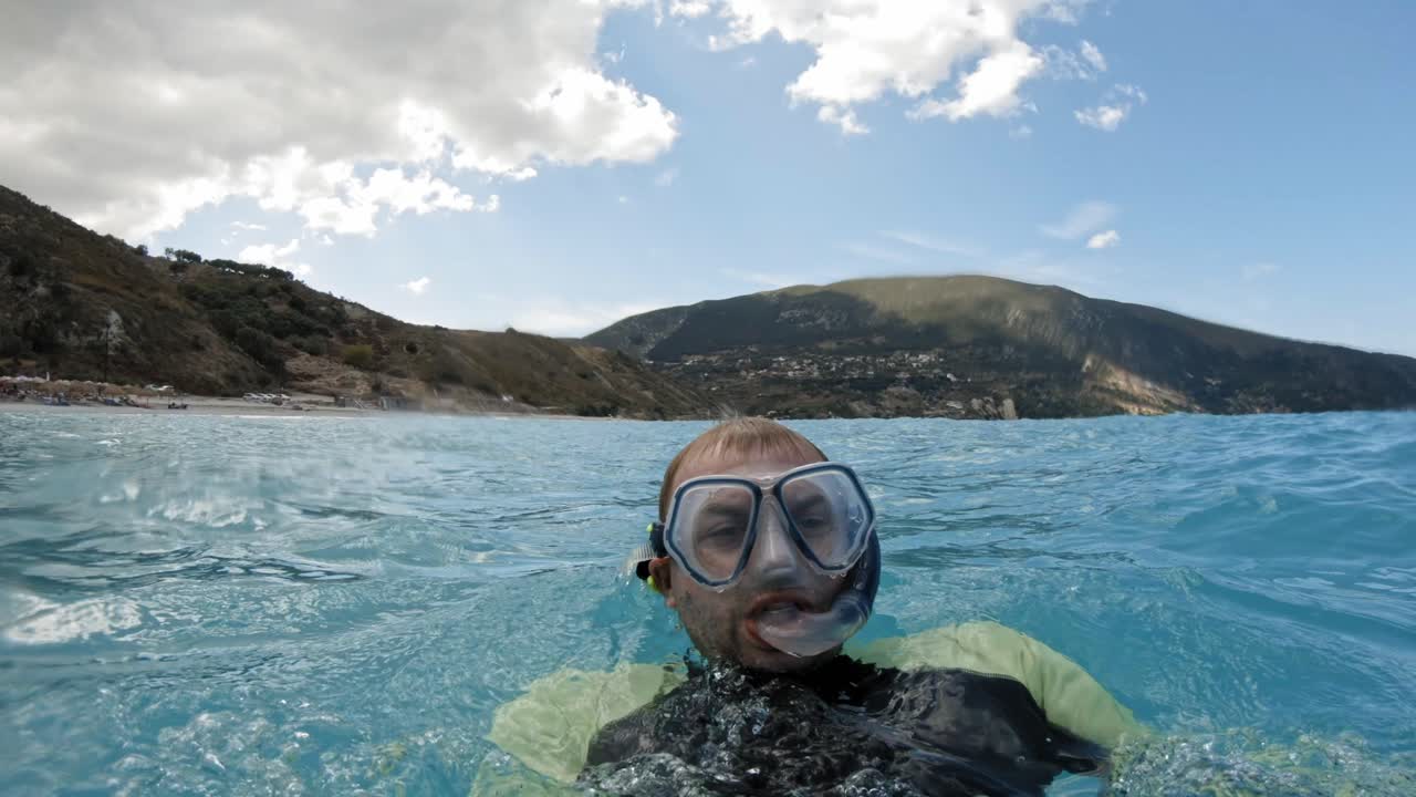 primer plano de un buceador equipado con máscara de buceo y tubo de respiración mientras nada en el mar