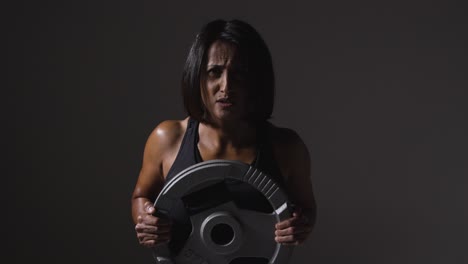 Studio-Shot-Of-Mature-Woman-Wearing-Gym-Fitness-Clothing-Lifting-Weights-For-Cardio-Exercise