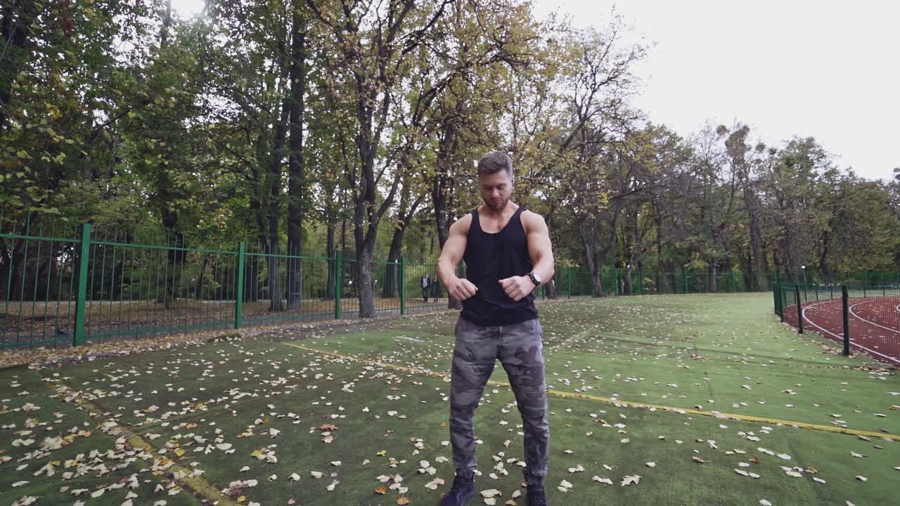 Handsome bearded sportsman outdoors. Muscular athlete doing exercises in the open air in autumn. Slow motion.