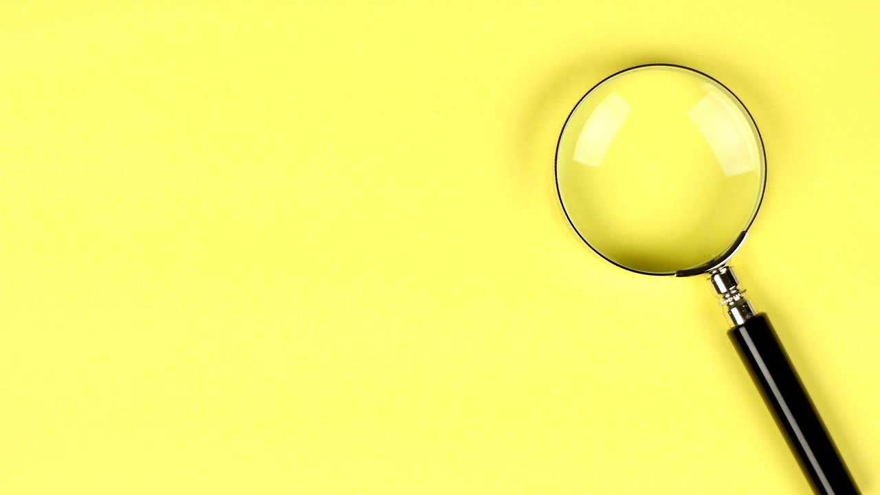 colocación a mano de una lupa sobre un fondo amarillo para mostrar la búsqueda o la investigación