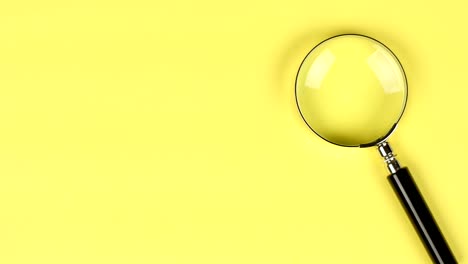 hand placing magnifier glass on yellow background to show search or investigation