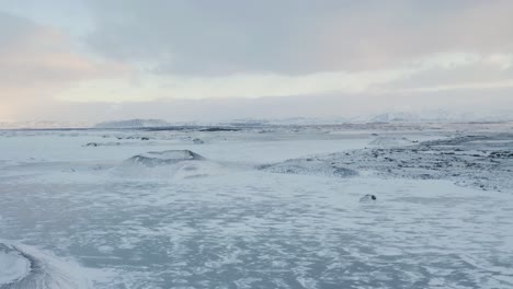drone flight over frozen my vatn lake and volcanic crater covered with snow during cold winter day - breathtaking winter scene of north iceland