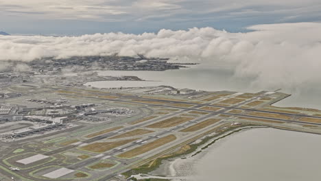 burlingame california antena v7 alto paso elevado ingold milldale y millbrae vecindarios, acercar y alejar el aeropuerto sfo junto a la bahía con espesas nubes en el cielo - filmado con mavic 3 cine - junio de 2022