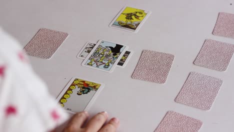 tarot reader flipping cards of celtic cross spread, over the shoulder shot