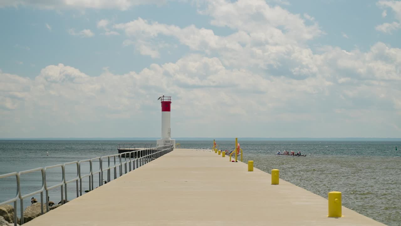Walking down a pier with a lighthouse at the end overlooking Lake Ontario in Oakville
