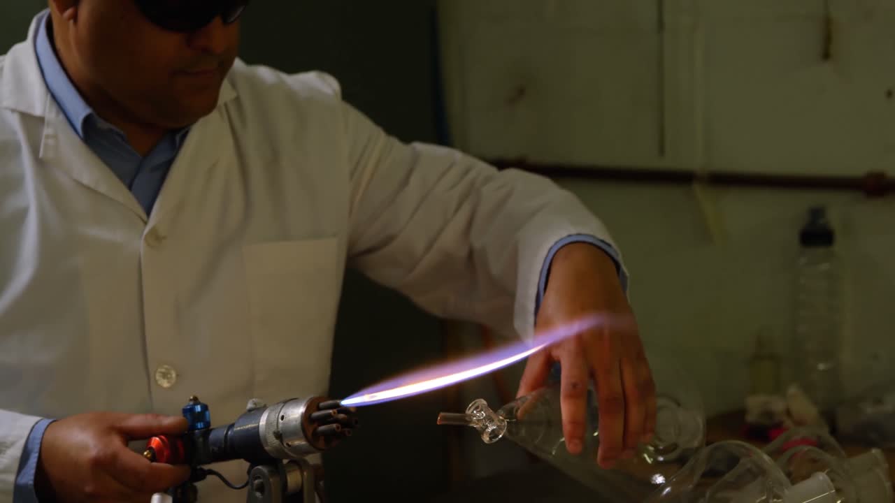 trabajador masculino maduro soplando vidrio en una fábrica de vidrio 4k