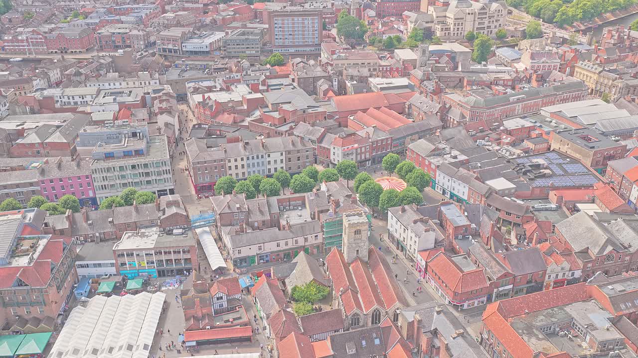 Drone footage over York shopping district, historic The Shambles, cobbled streets, red rooftops, vibrant tourism hub in summer, England