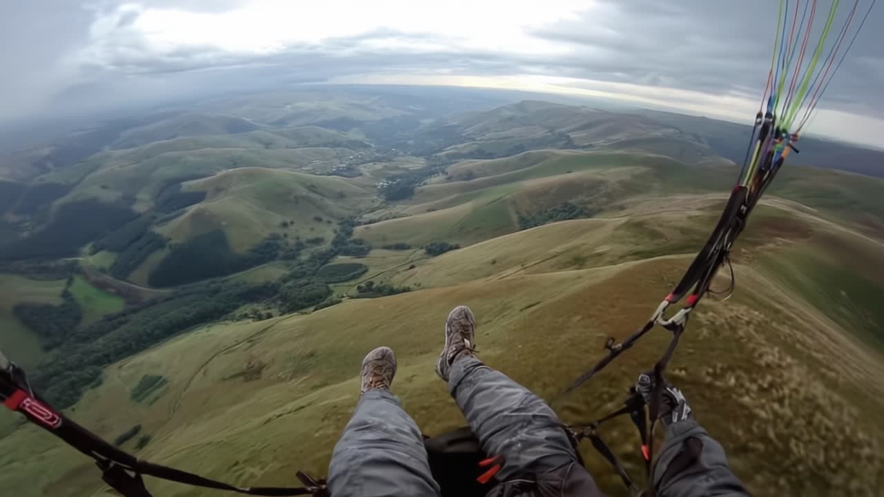 A breathtaking view from above captures the exhilarating experience of paragliding over rolling green hills and valleys, showcasing the beauty and vastness of nature from a thrilling vantage point