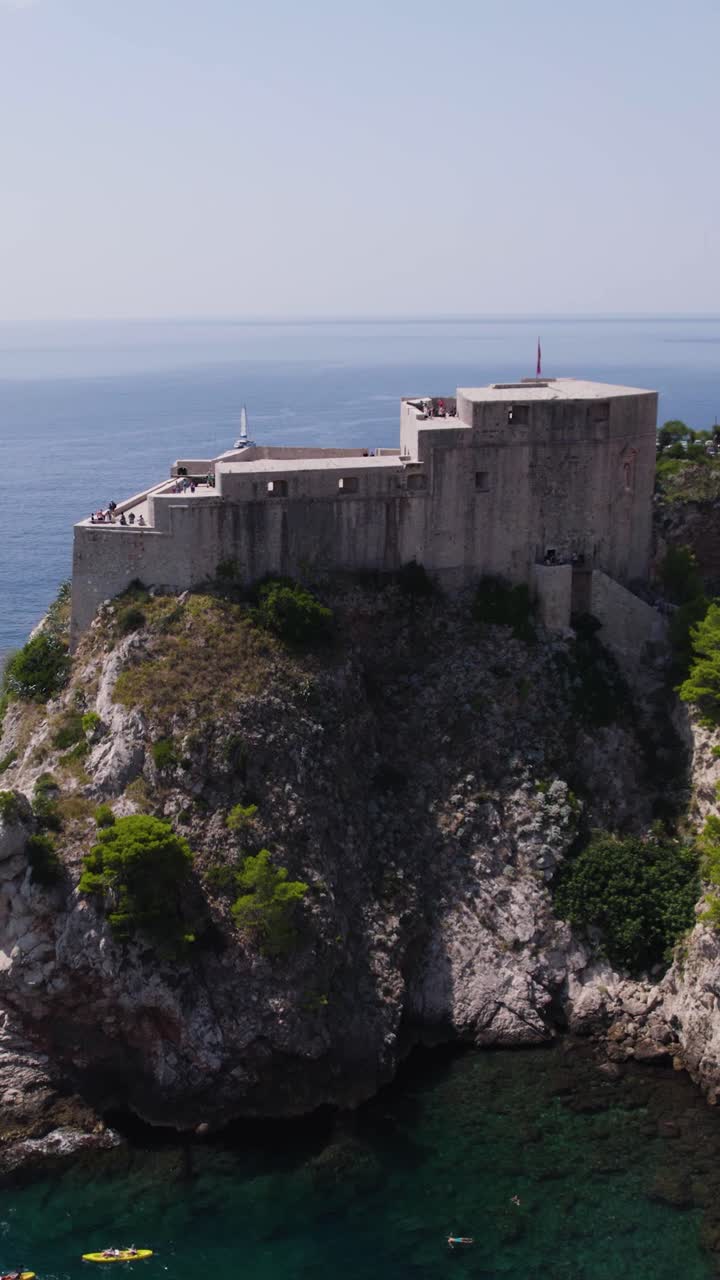 Historic Fort Lovrijenac on a cliff situated by the clear Adriatic Sea in Dubrovnik. Aerial, Vertical Video