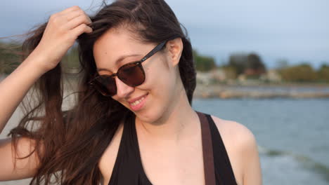 Pretty-Young-Girl-In-Sunglasses-Brushing-Her-Hair-With-Fingers-Blowing-In-The-Wind