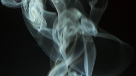 el humo plateado se eleva lentamente con gracia hacia arriba. el humo del cigarro sopla de abajo hacia arriba. primer plano, aislado sobre un fondo negro