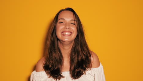 smiling woman in a white top against a yellow background