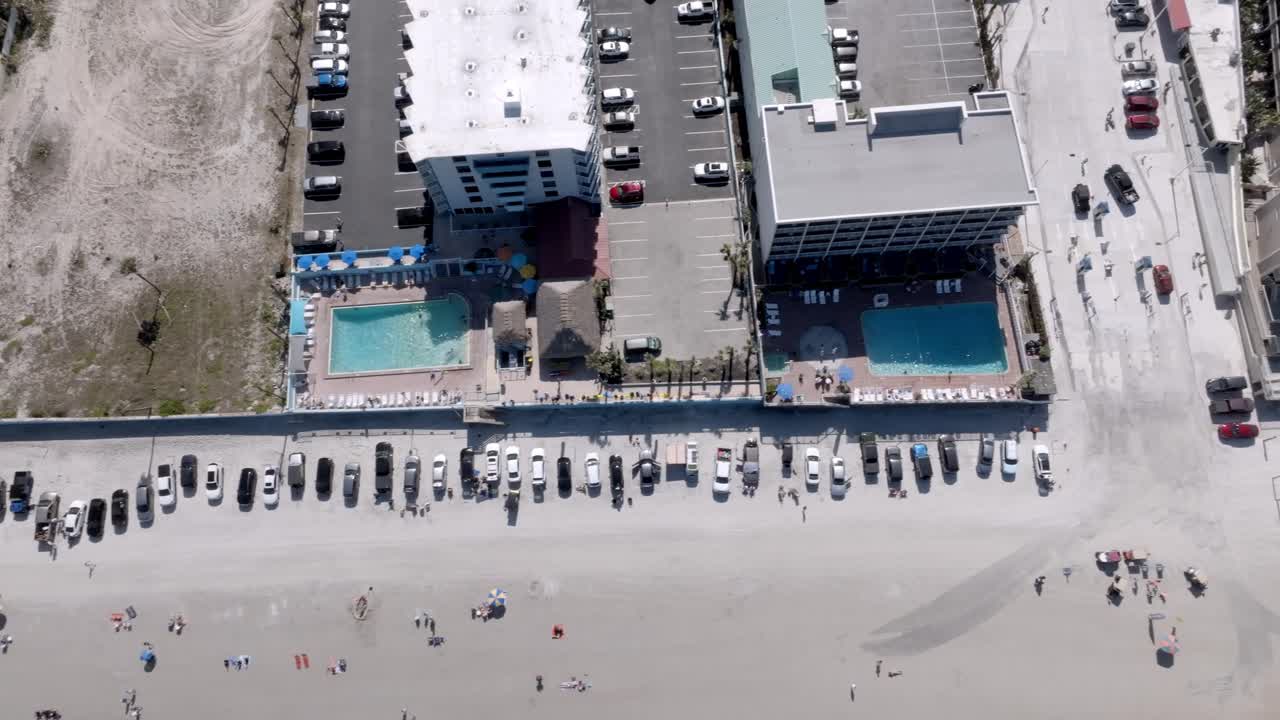 Daytona Beach, Florida with vehicles, and people on the beach with drone video overhead looking down.