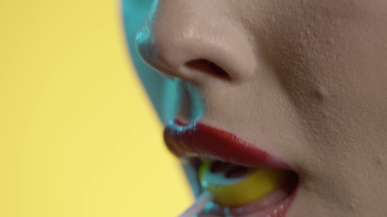donna che lecca il gelato alla ciliegina con seduzione, bocca in primo piano su sfondo giallo