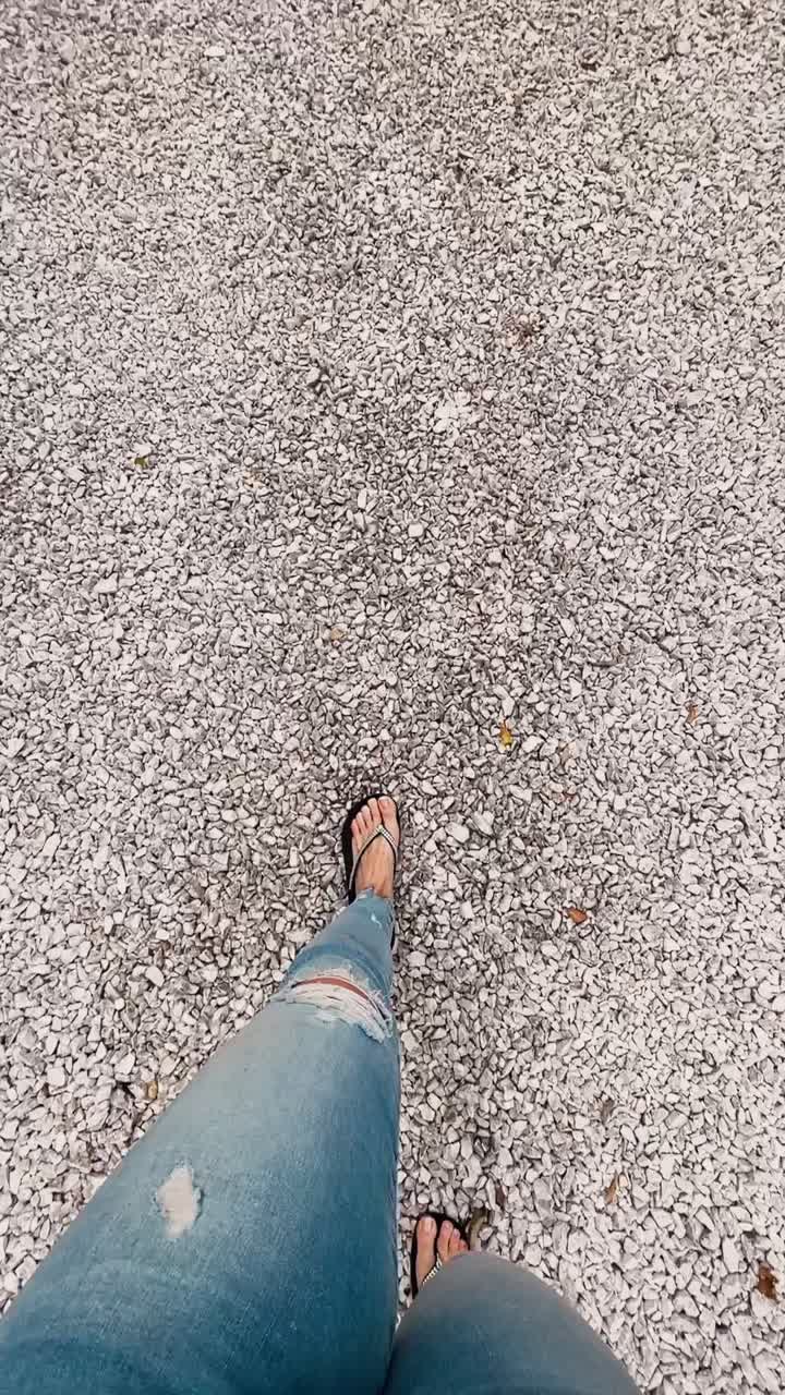 persona de pie en la grava con flores y sandalias