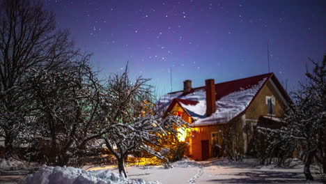 Zeitraffer-Von-Sternen-Und-Nordlicht,-Die-Sich-Nachts-über-Ein-Mit-Schnee-Bedecktes-Haus-Bewegen