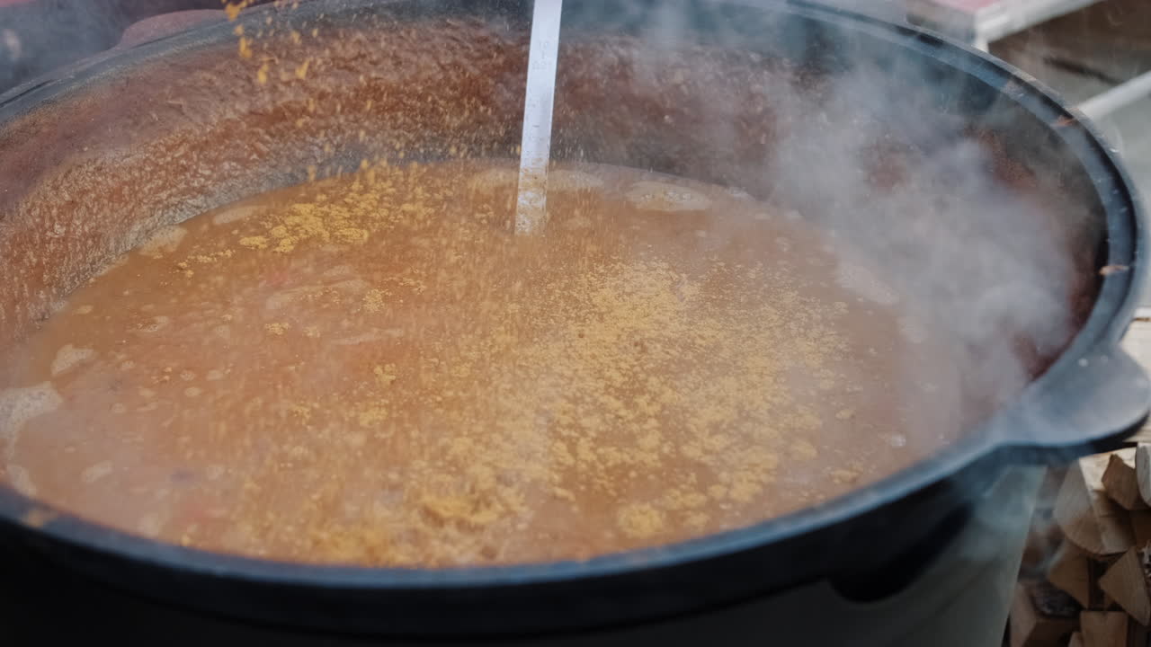 cocción al aire libre de sopa en una gran olla de hierro fundido