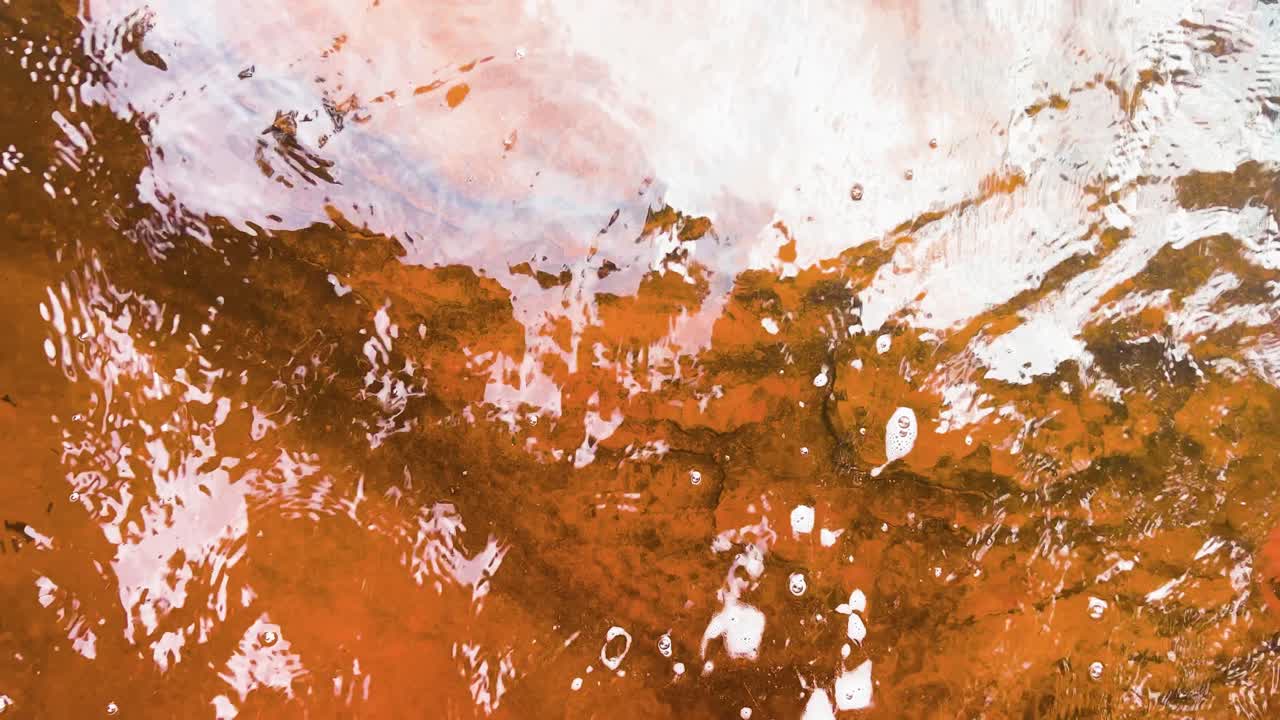 L'acqua scorre lungo un fiume rosso, naturalmente colorato dagli alcali degli alberi vicini, nel profondo della foresta pluviale amazzonica