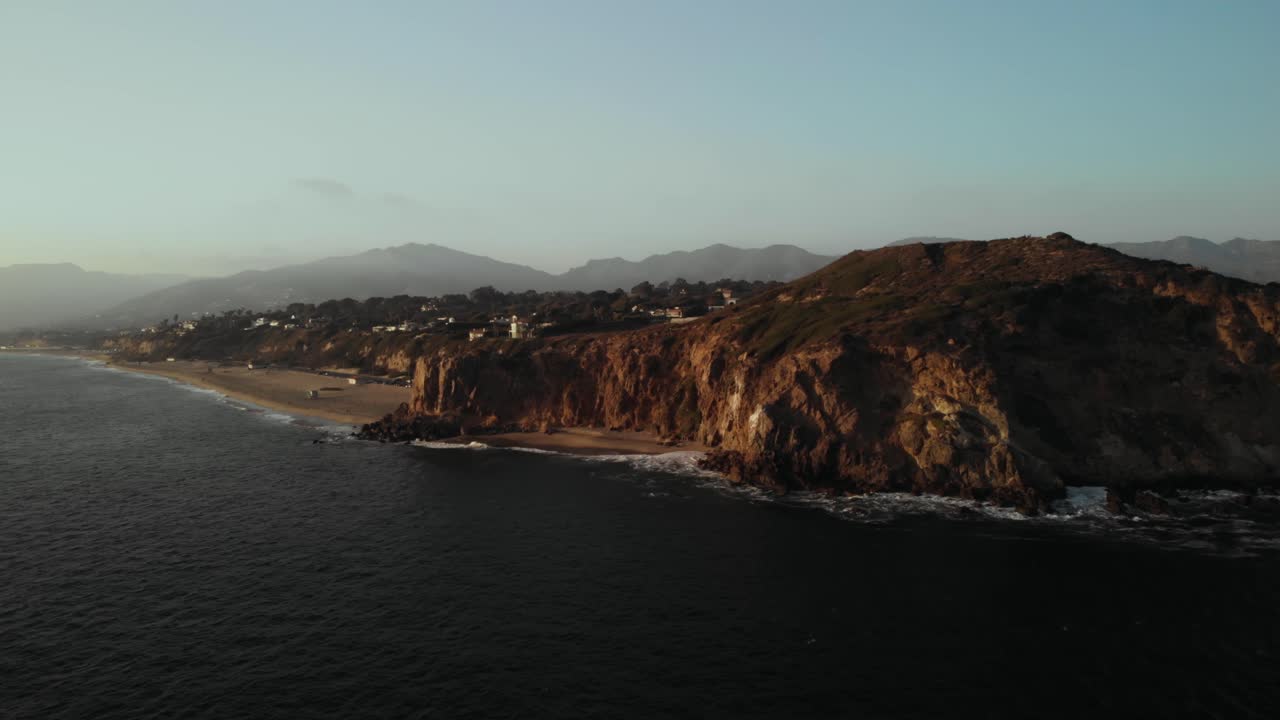 활기찬 태양이 지는 조용한 저녁에 파도가 바위에 부딪히면서 캘리포니아 말리부에 있는 포인트 둠 절벽의 공중 촬영
