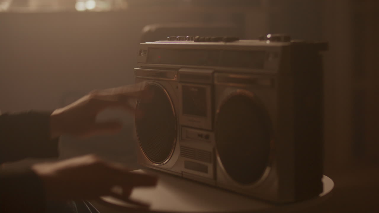 Young Guy Inserting Cassette Tape into Retro Boombox, Turning On Music