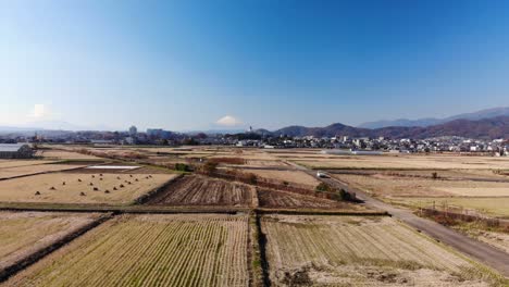 日本东京 - 一辆行驶的汽车在狭窄的道路上经过开放的大米田与山