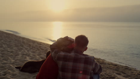 una pareja romántica mirando el amanecer en el océano. un hombre abrazando a una mujer en la playa.