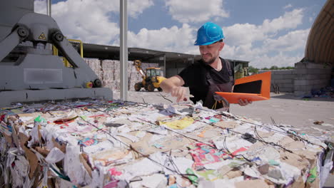 Man-checking-recycled-pressed-paper-bales,-makes-notes-in-orange-file